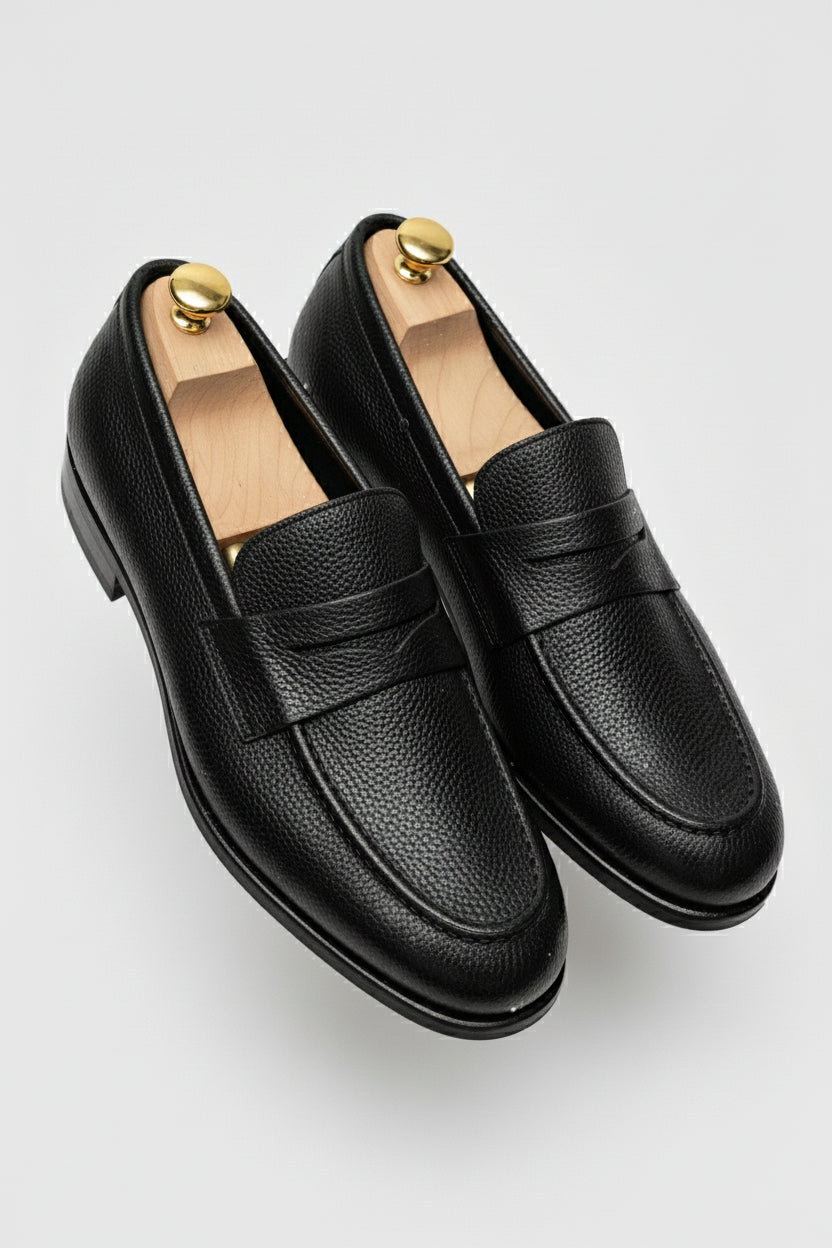 Black textured leather slip-on loafers with elegant design and comfortable fit.