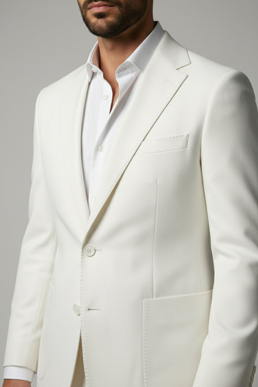 Man wearing sophisticated white two-piece performance suit with peak lapels and tailored fit.