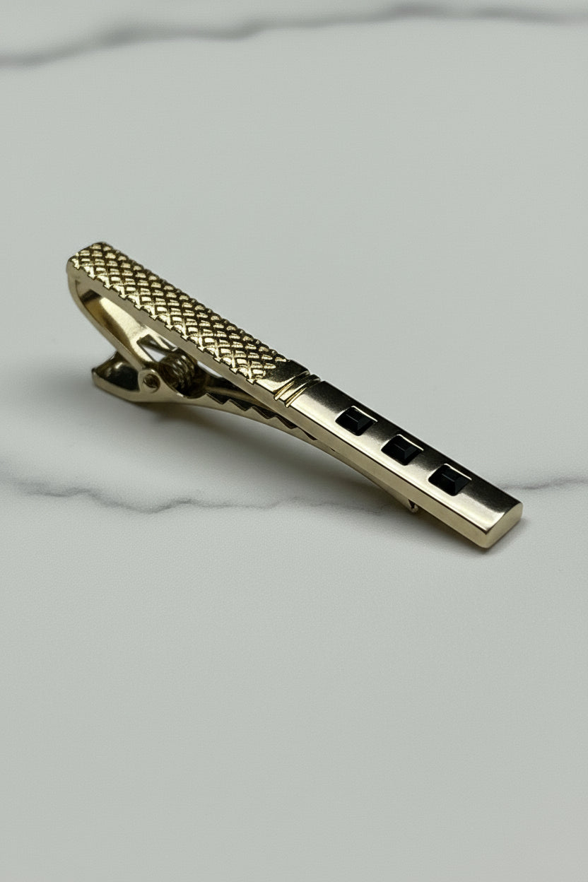 Gold textured tie clip with elegant design, perfect for formal occasions.