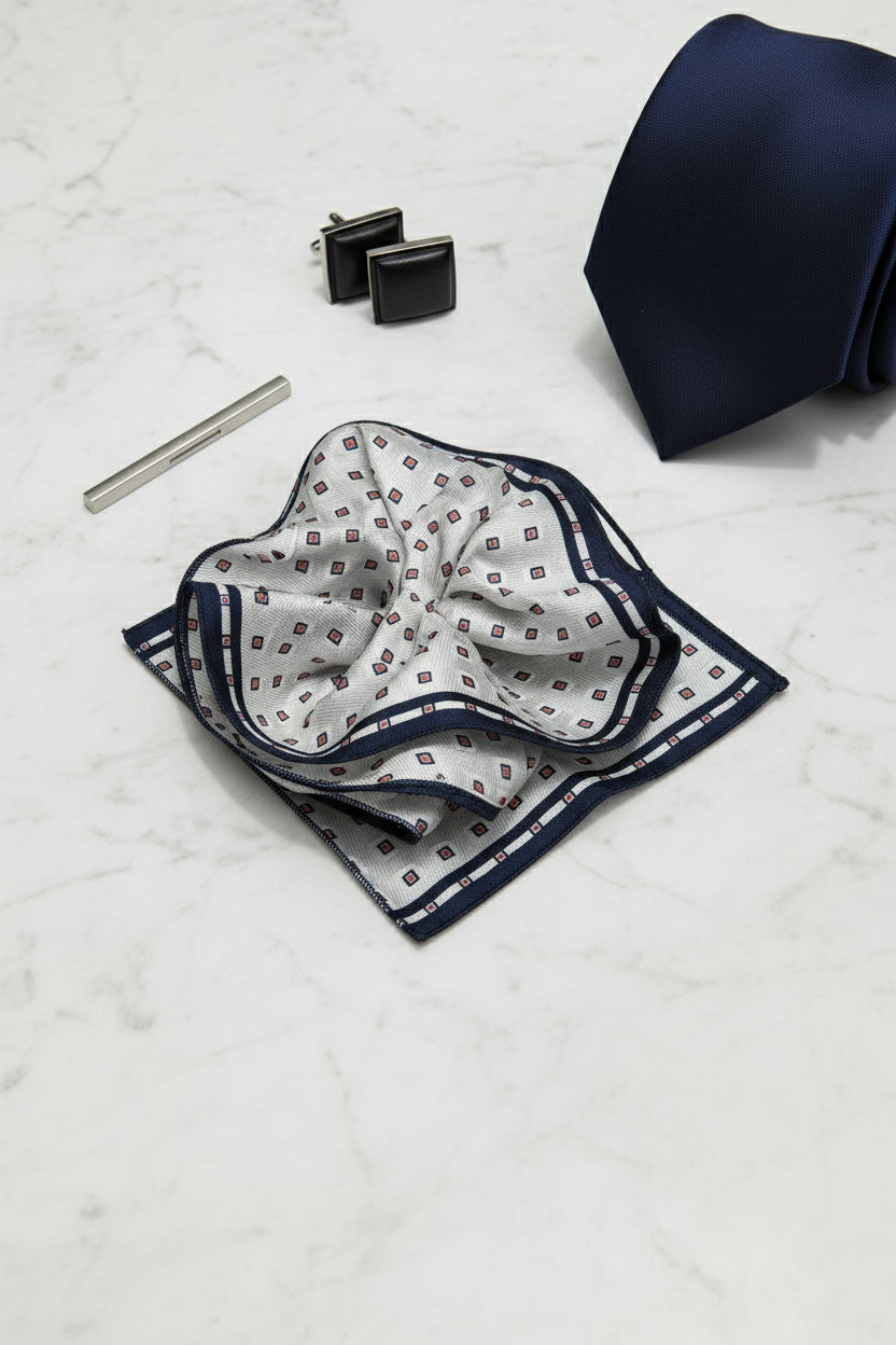 White silk pocket square with geometric print and navy border for formal wear.