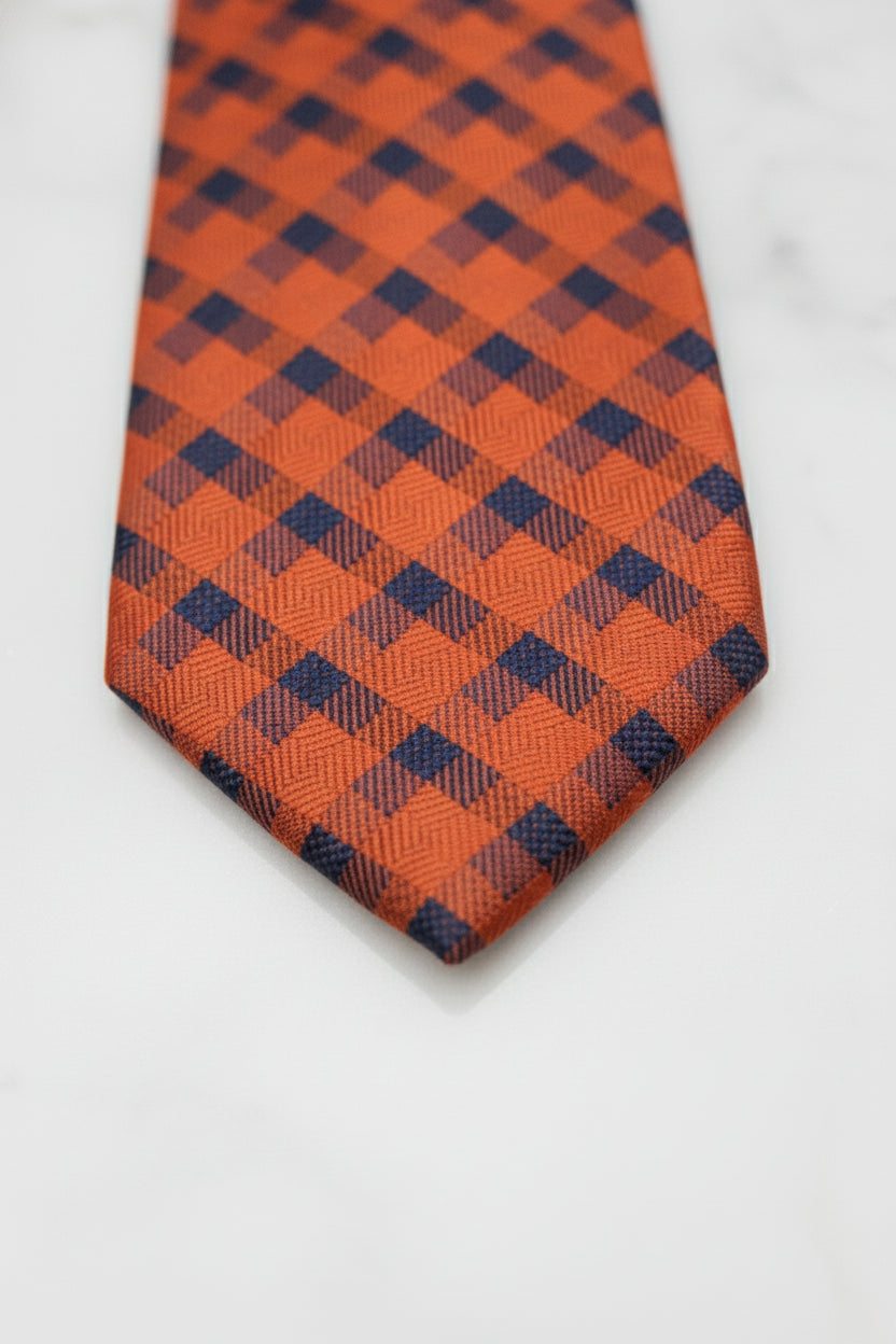 Orange silk tie featuring geometric pattern in navy blue for formal occasions.