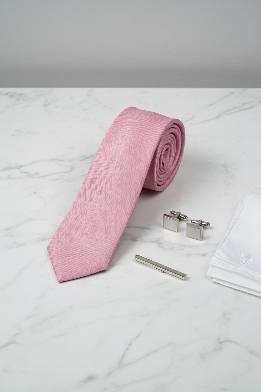 Textured pink silk tie displayed with silver cufflinks and a pocket square.