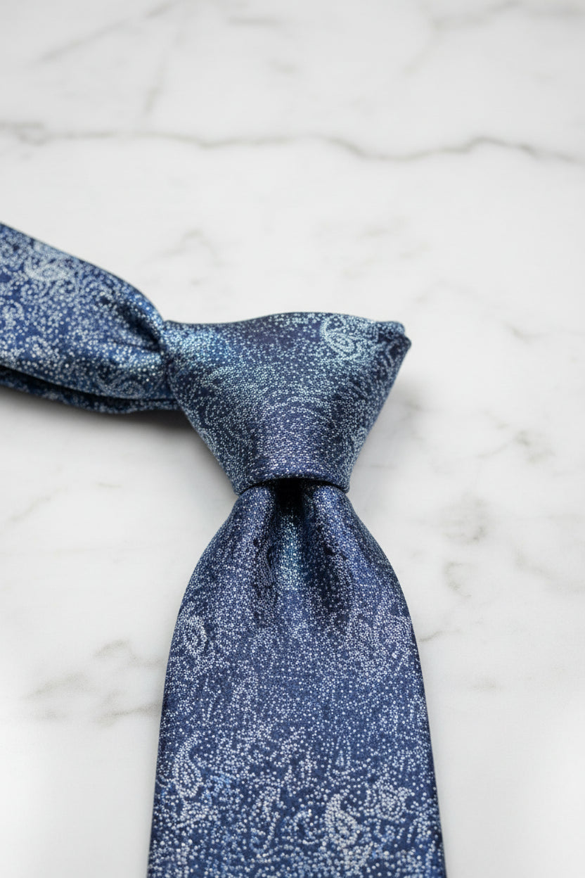 Navy paisley pattern silk tie elegantly knotted on marble surface.