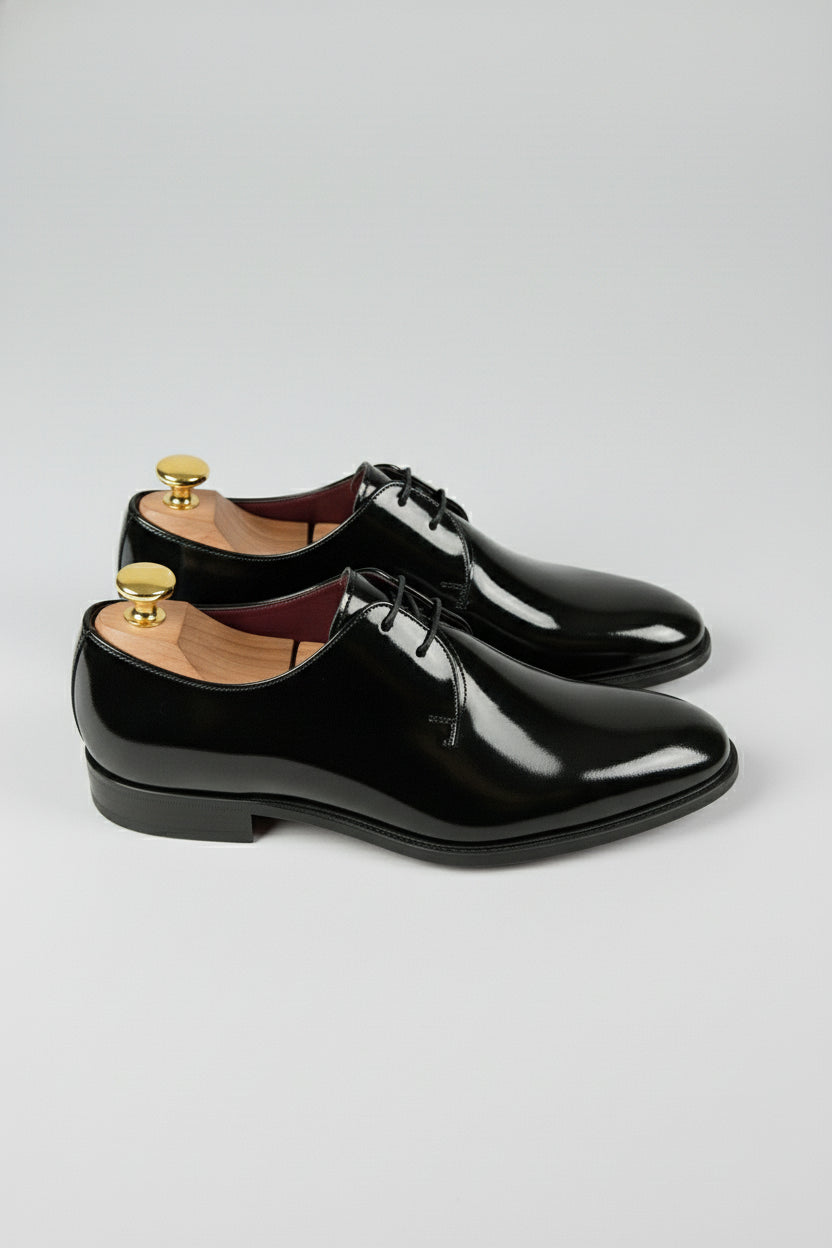 Black patent leather Oxford shoes with lace-up design, perfect for formal occasions.