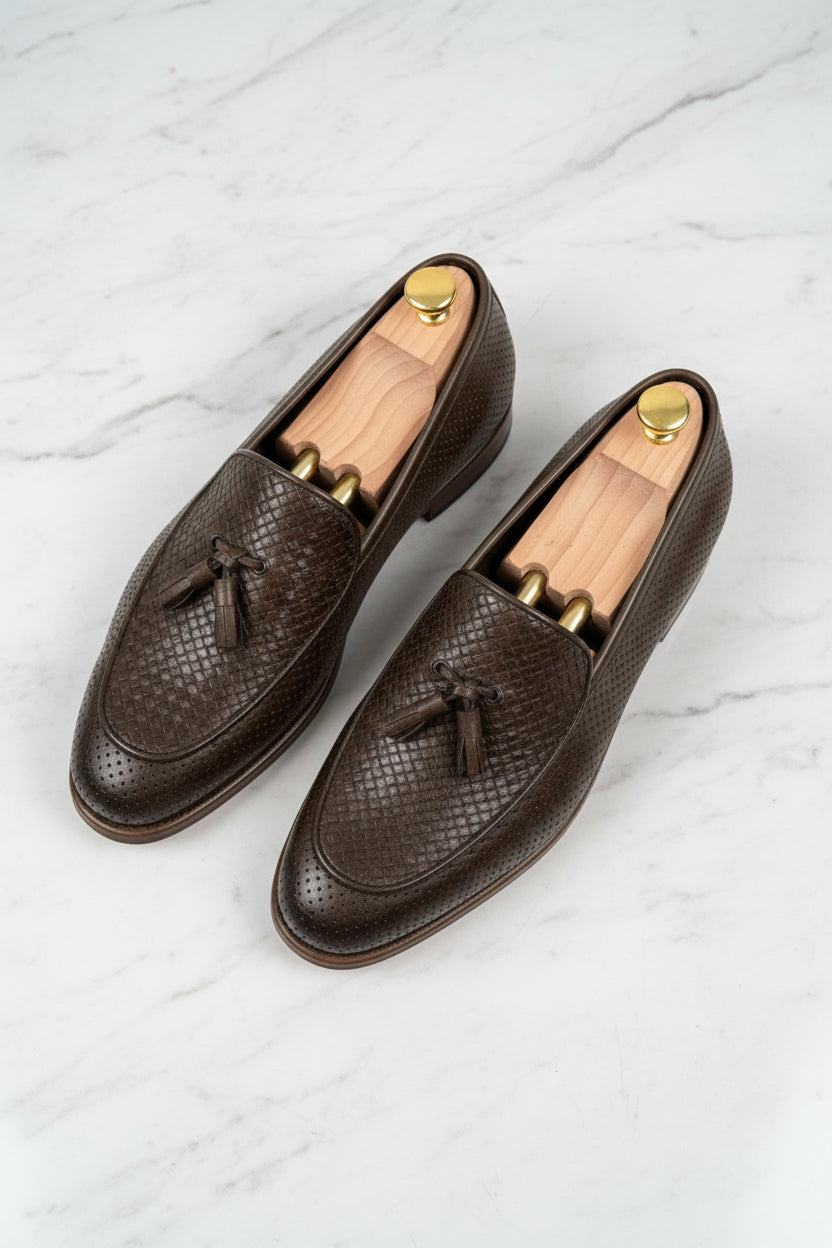 Dark brown woven leather loafers with tassel detail and slip-on design.