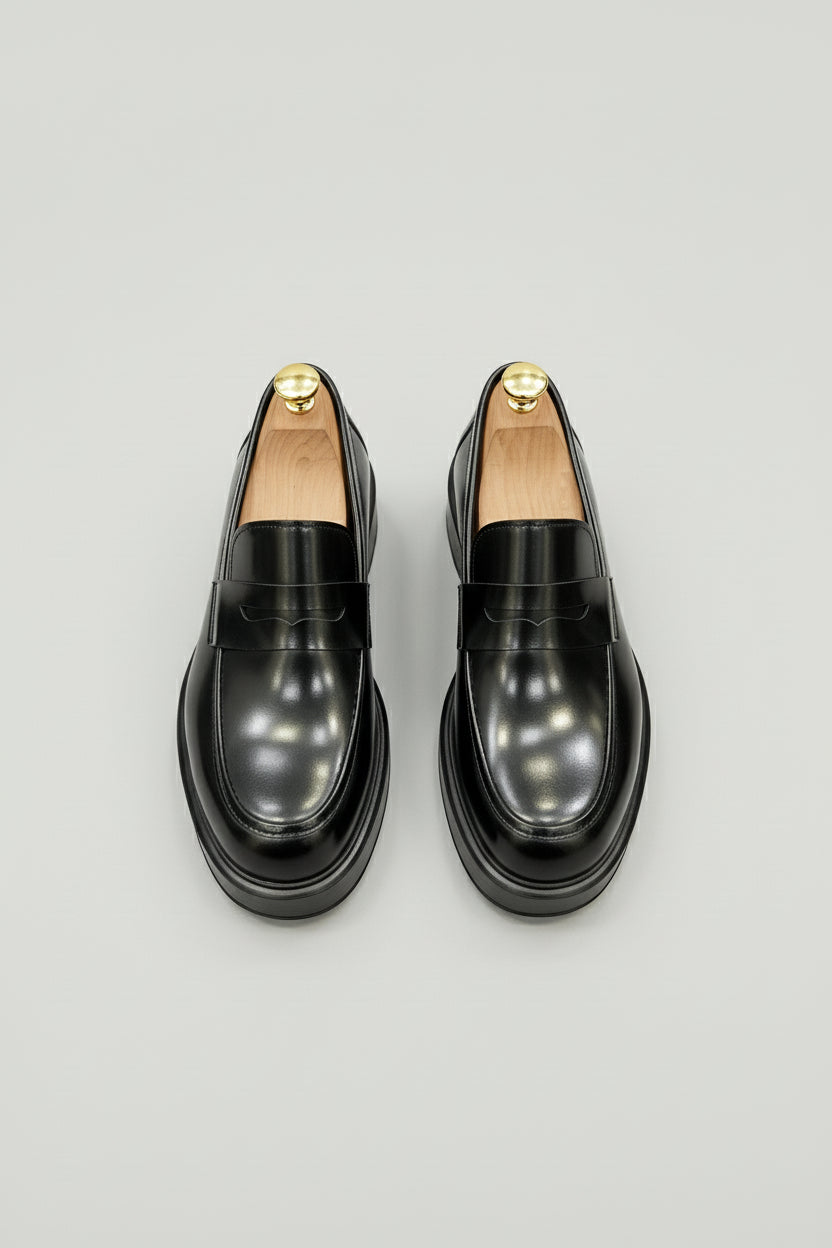 Black glossy leather loafers with raised sole and polished finish for men.